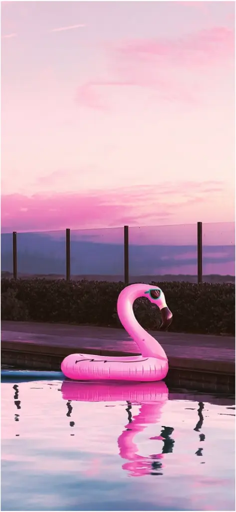 aufblasbarer flamingo im pool bei sonnenuntergang