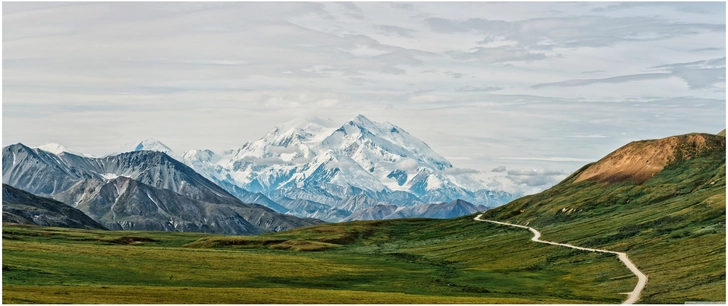 berglandschaft mit schneebedeckten gipfeln und gruener wiesenflaeche
