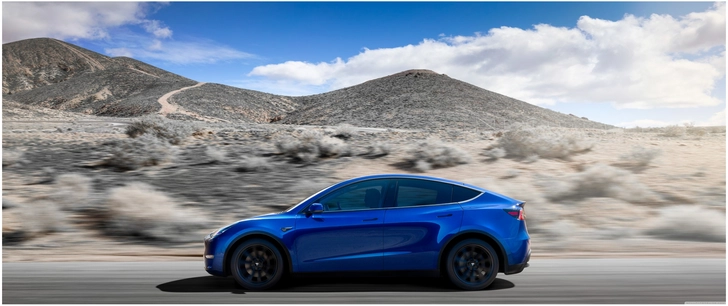 blauer tesla model y auf landstrasse mit huegeln