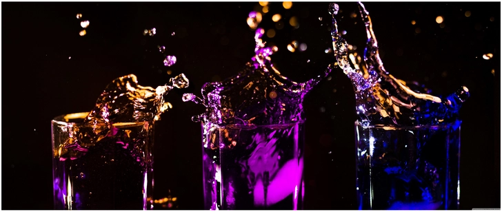 bunte spritzer aus glaesern bei nacht