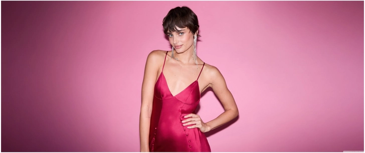 elegantes model rotes kleid vor rosa hintergrund