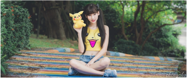 froehliche junge frau mit pikachu plueschtier in buntem park