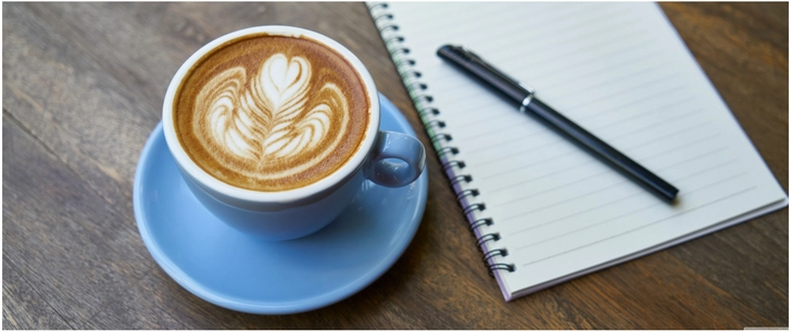 gemuetliche kaffeetasse mit kunstschaum und notizblock