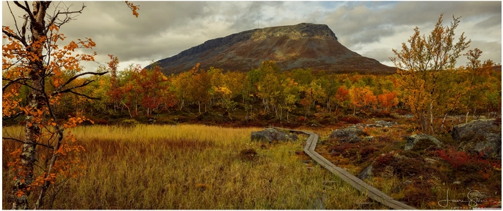 herbstliche landschaft mit majestaetischem berg und holzsteg