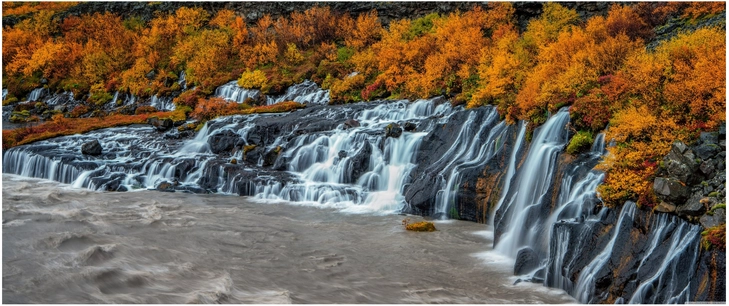 herbstlicher wasserfall mit buntem laub und fliessendem wasser