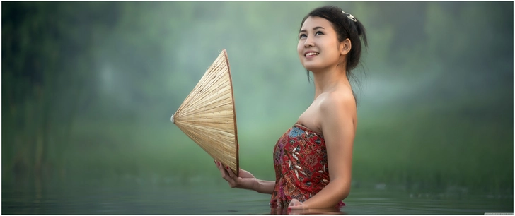 junge frau im wasser mit traditionellem hut