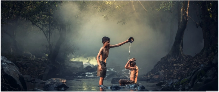 jungen spielen im bach mit wasser spritzen