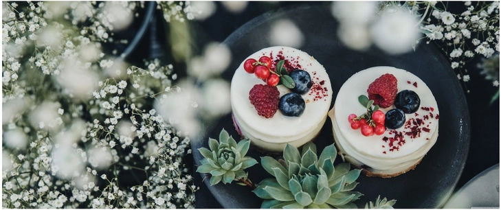 koestliche mini cheesecakes mit frischen beeren und blumen