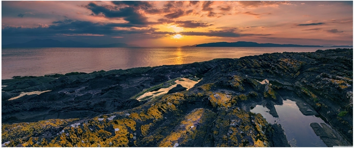 kuestenlandschaft mit sonnenuntergang und felsen in schottland