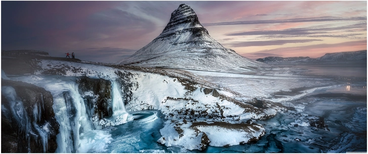 majestetischer berg und gefrorene wasserfaelle in winterlicher landschaft
