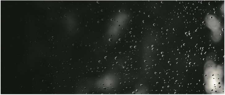 nasse fensterscheibe mit wassertropfen auf schwarzem hintergrund
