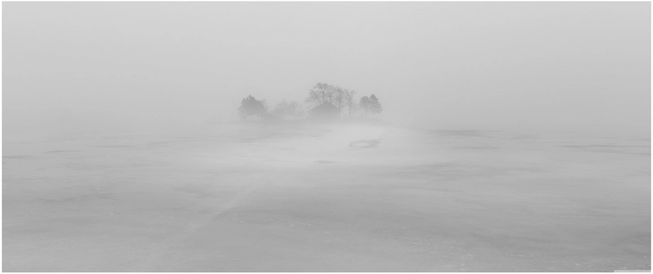 nebelverhangene winterlandschaft mit einsamen haus und baeumen