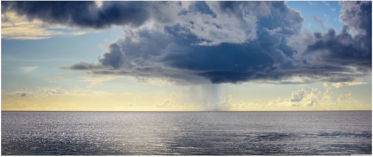 regenwolken ueber dem meer bei sonnenuntergang