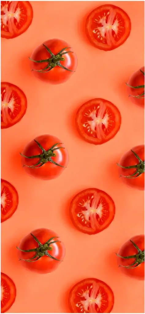 rote tomaten und tomatenscheiben auf korallenfarbenem hintergrund