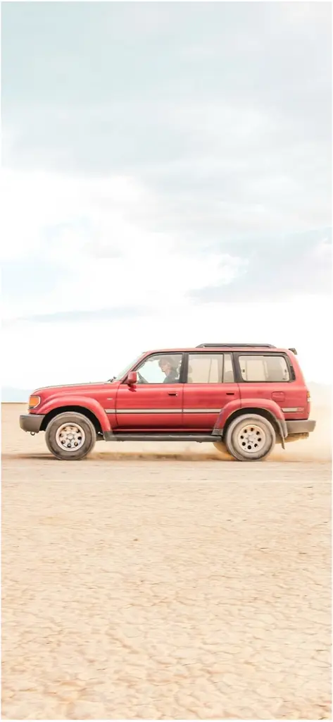 roter suv faehrt durch die wueste