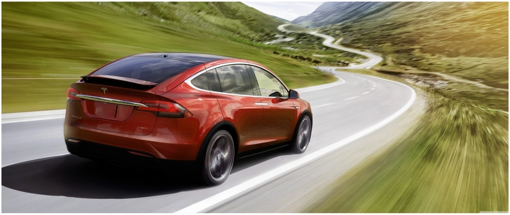 roter tesla model x auf malerischer bergstrasse