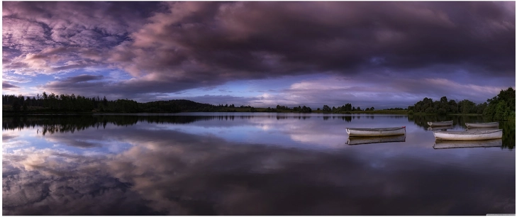 ruhige seelandschaft mit boote und dramatischem himmel