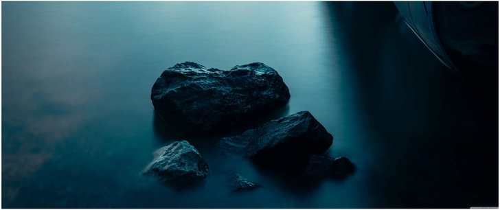 ruhige wasseroberflaeche mit felsen in sanftem licht