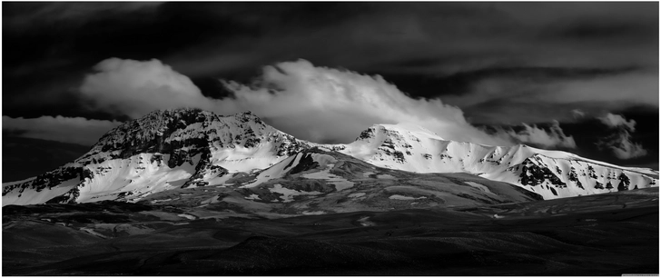 schneeberglandschaft in schwarzweiss mit dramatischen wolken