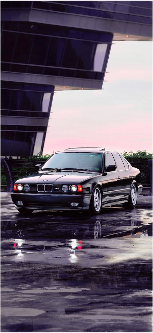 schwarzer-bmw-auf-nassem-asphalt-moderne-architektur
