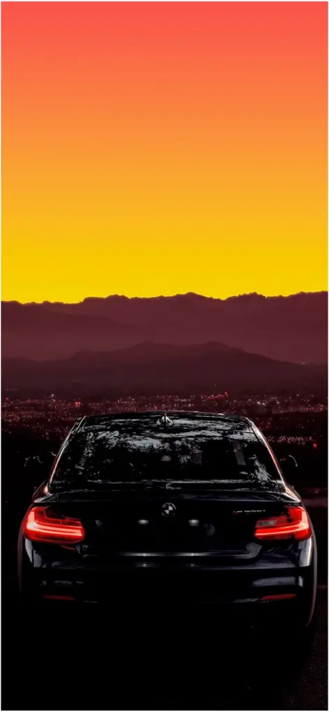 schwarzer bmw bei sonnenuntergang ueber der stadt