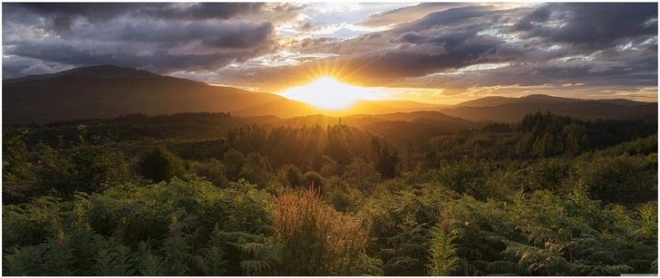 sonnenaufgang ueber schottischen bergen und gruener natur
