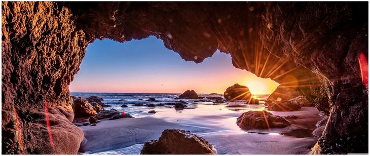sonnenuntergang in einer strandhoehle mit felsen