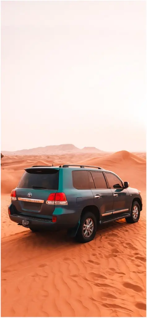 suv in der wueste mit sandduenen im hintergrund