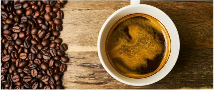 tasse kaffee und kaffeeboenen auf holz