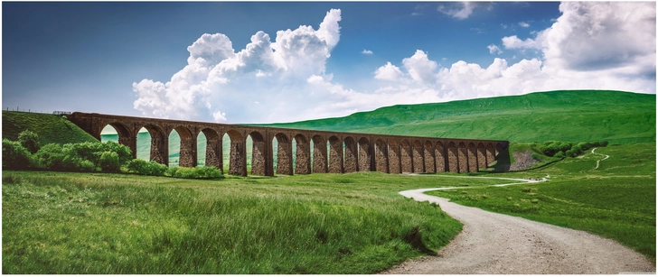 viadukt in gruener landschaft mit wolken