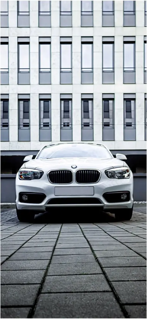 weisser bmw vor modernen gebaeuden auf grauem gehweg