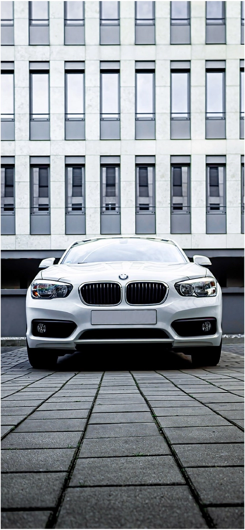 weisser-bmw-vor-modernen-gebaeuden-auf-grauem-gehweg
