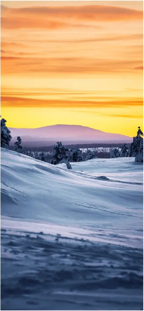 winterlandschaft bei sonnenuntergang mit schneebedeckten huegeln