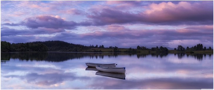 zwei boote auf ruhigem wasser mit reflektierendem himmel