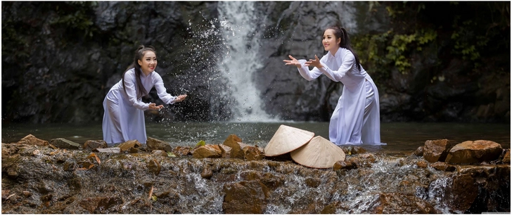 zwei frauen spielen am wasserfall in der natur