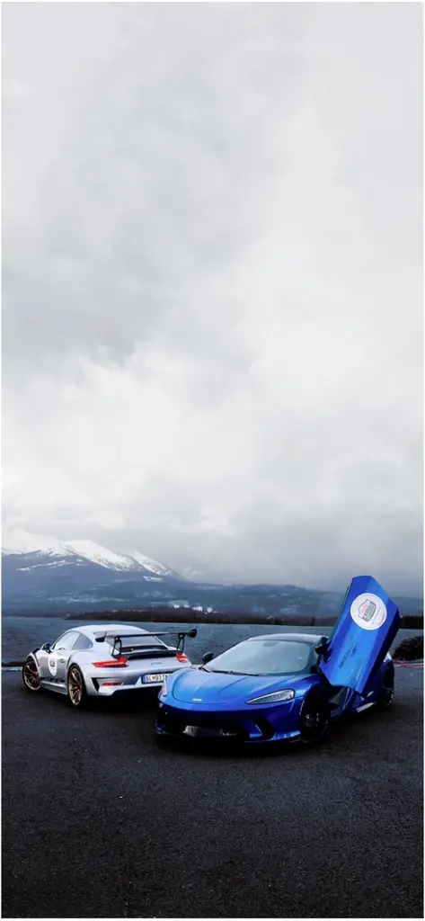 zwei sportwagen vor berglanschaft